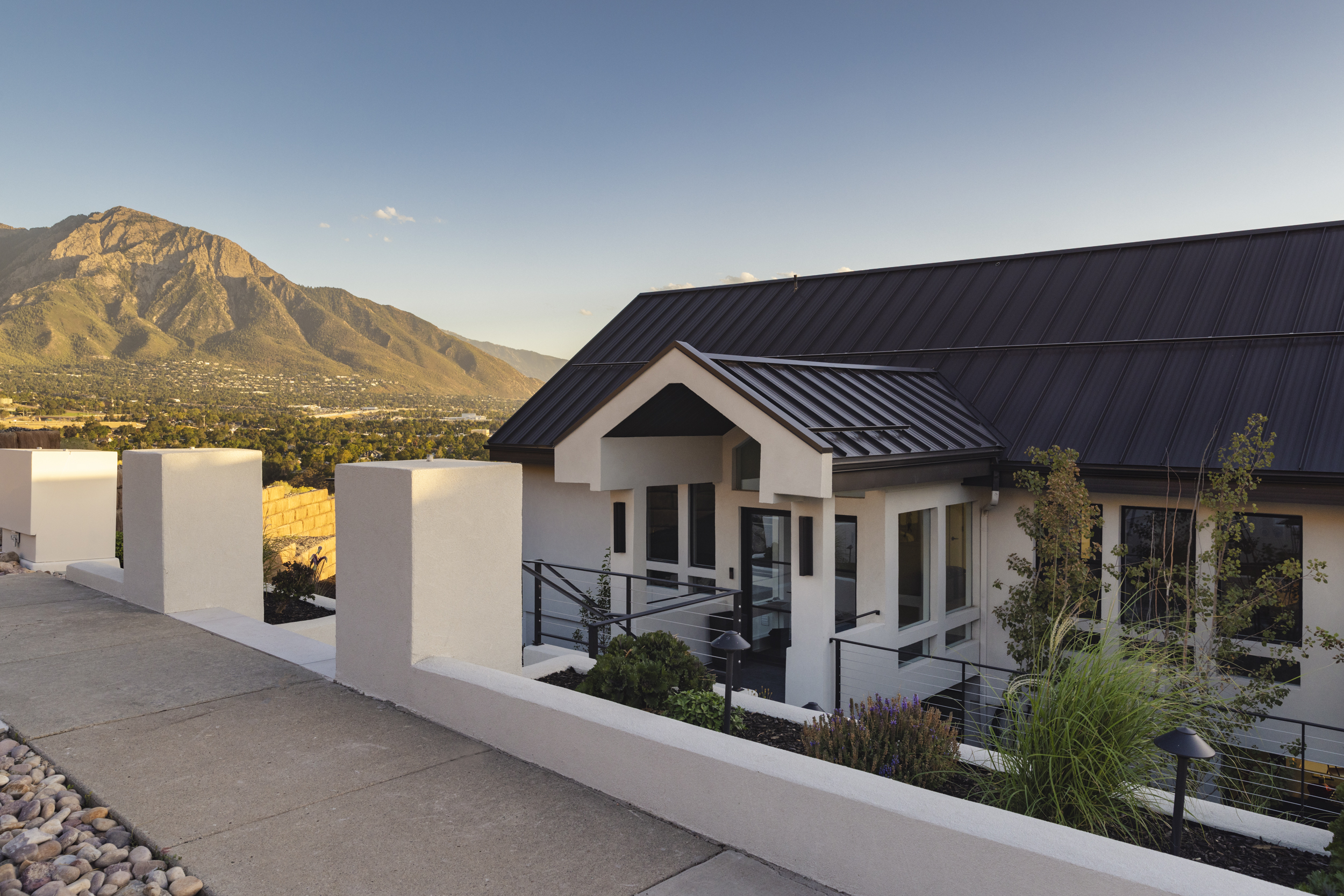 Landscaped front entry and steel roof with mountains beyond