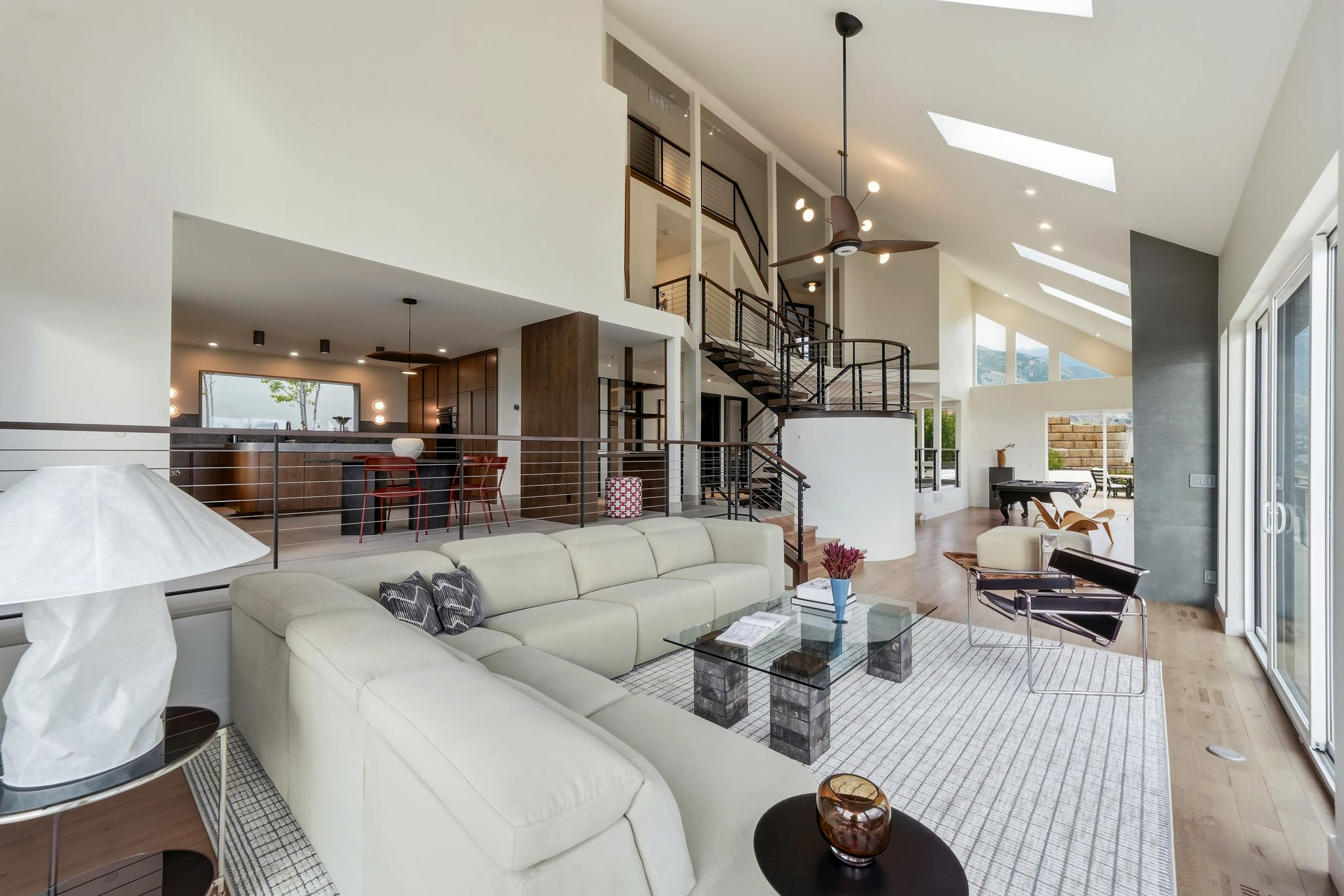 Light-filled living room with vaulted ceilings, open kitchen and sculptural staircase