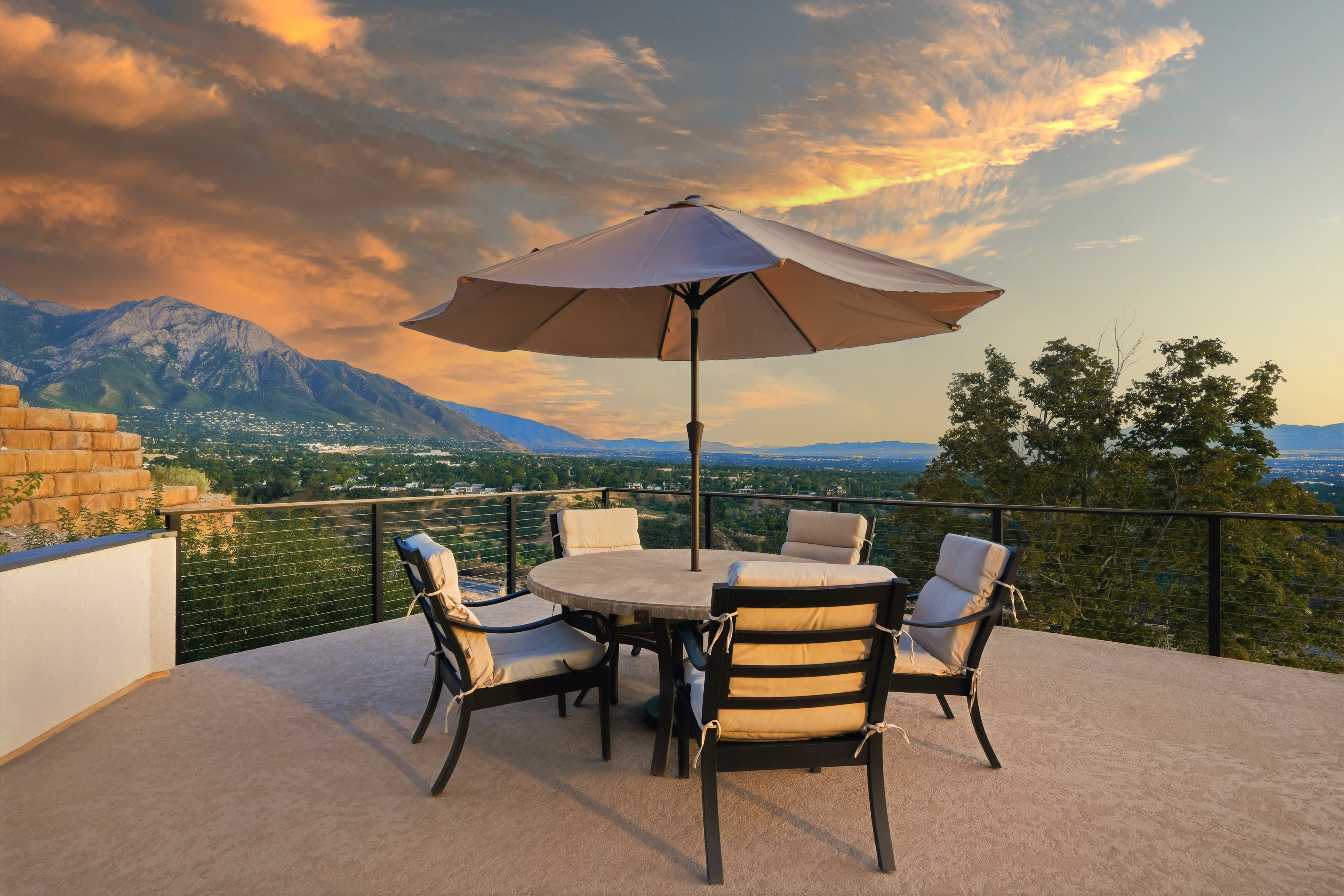 Outdoor dining area with umbrella, fire pit and mountain view at sunset