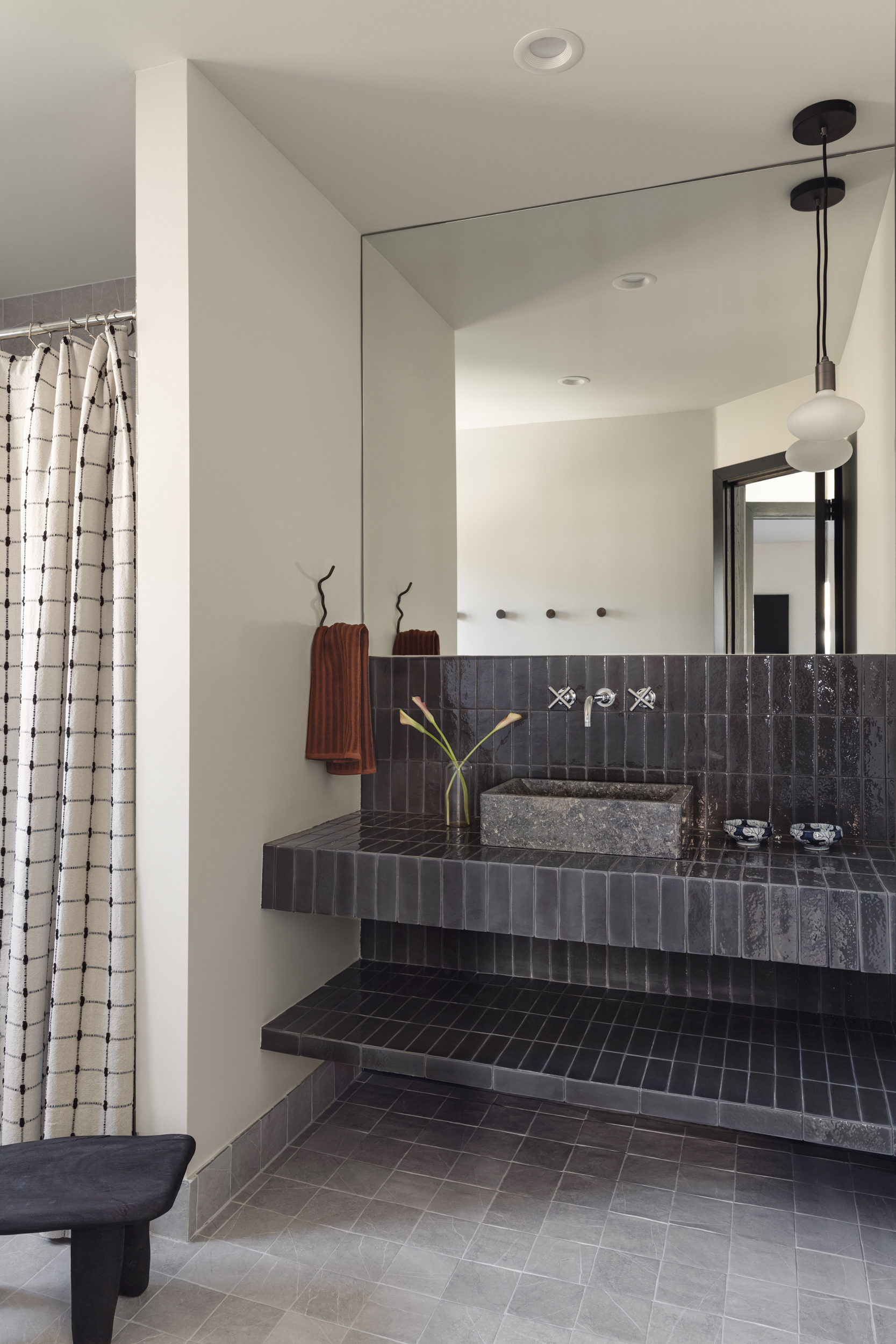 Dark tile bathroom with a sculptural vanity and shower